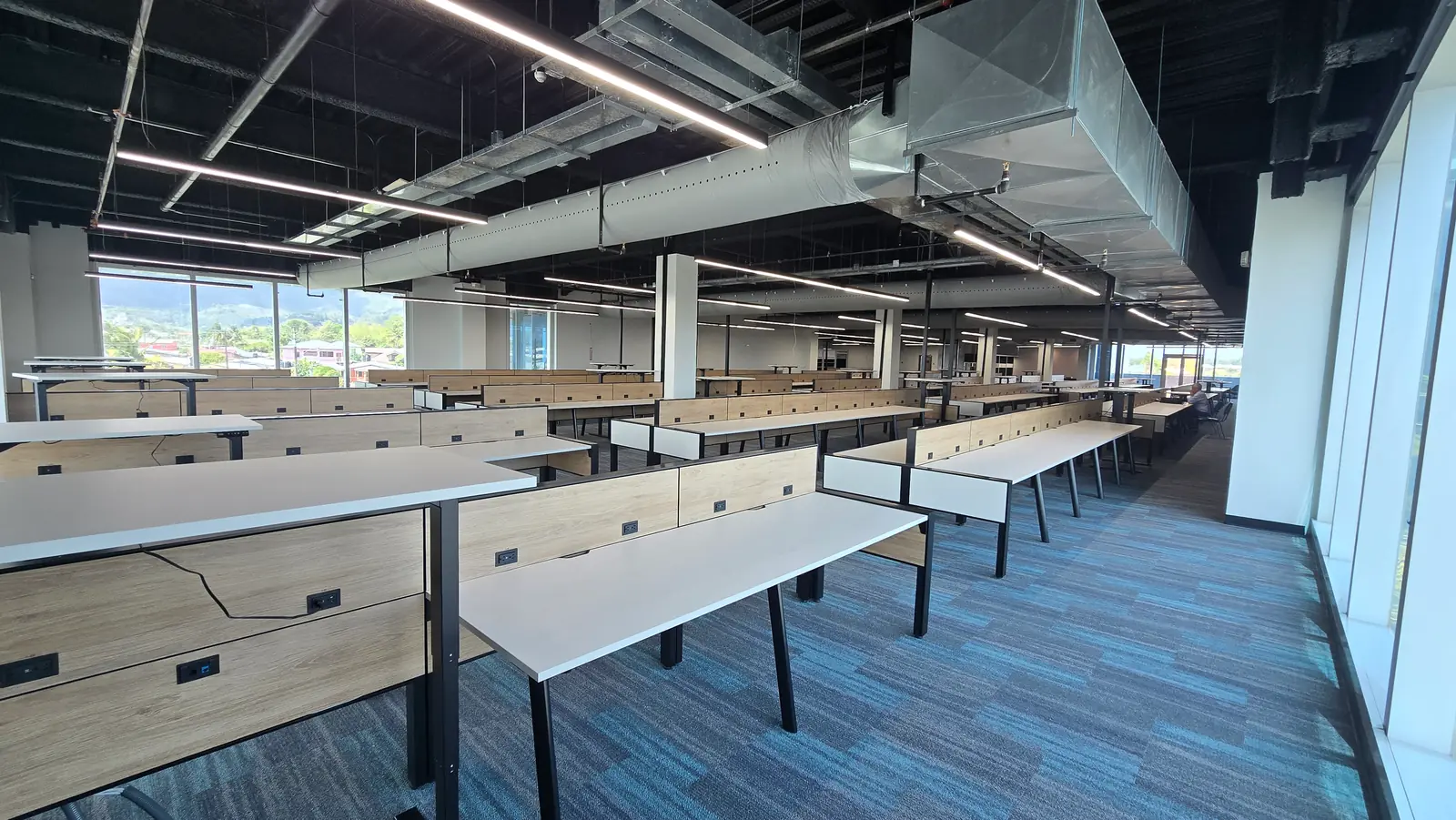 A large fitted operations floor in Trinidad, with the Northern Range visible through the windows