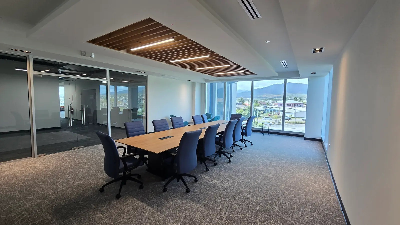 A meeting room with a long table and a view of the hills